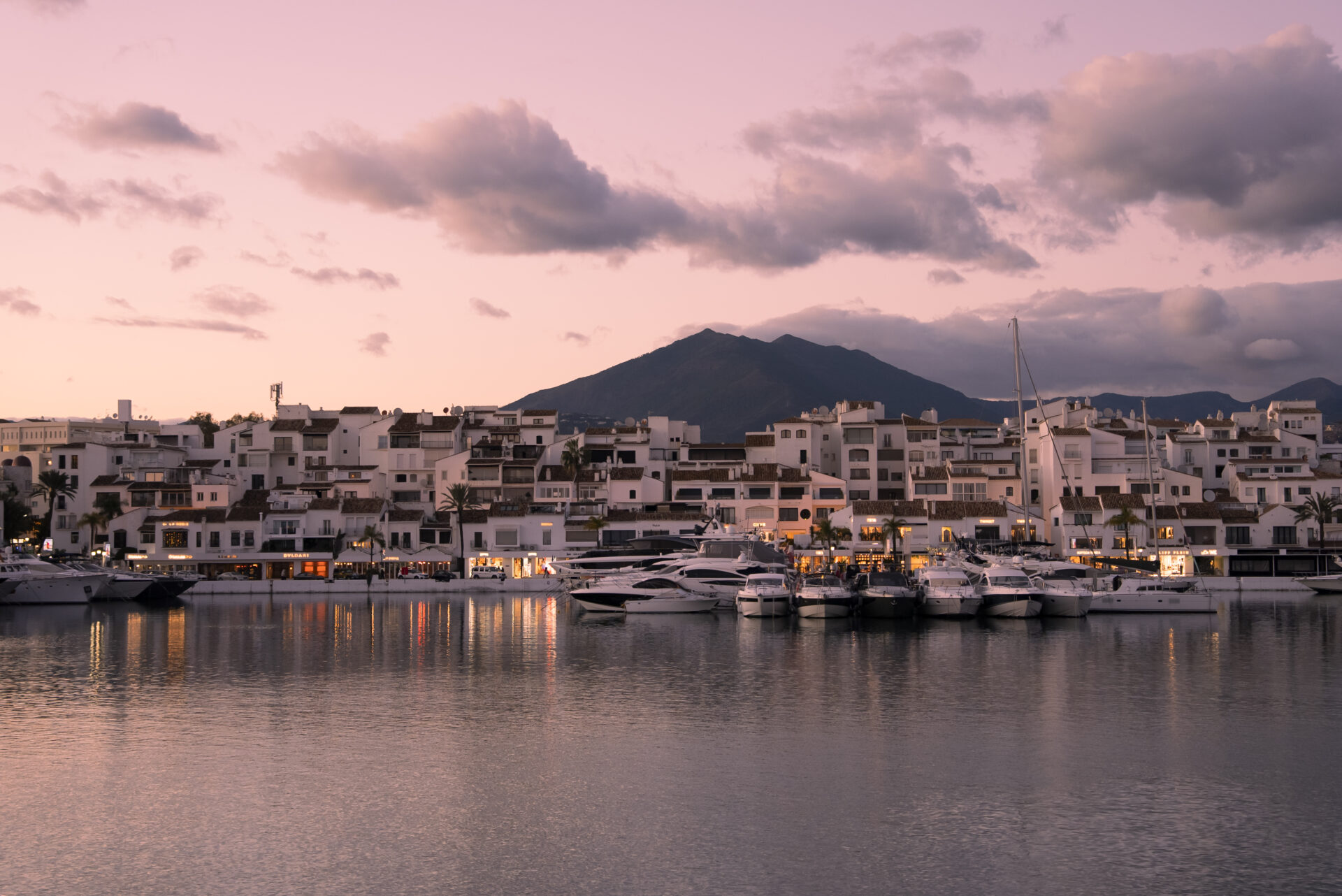 Puerto Banús marina with yachts, waterfront buildings, and La Concha mountain at sunset in Marbella
